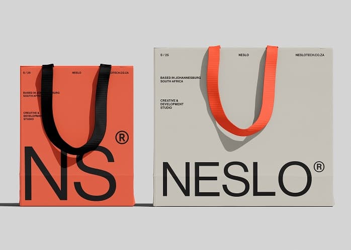 Two Neslo tote bags: the NS mark in the brand's coral accent, and the full wordmark in warm grey
